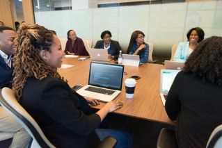 A diverse group of professionals working together in a modern conference room with laptops.